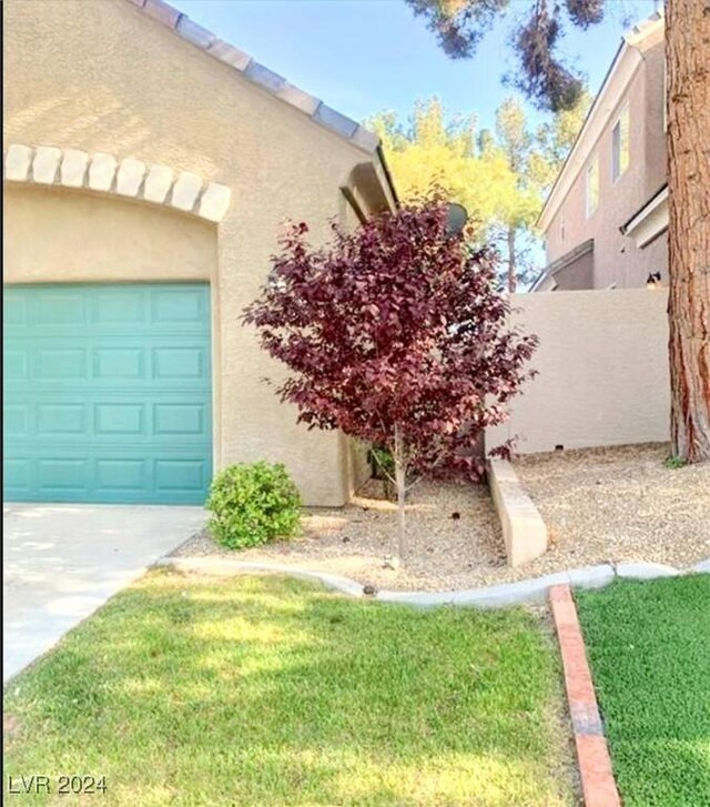 view of side of home featuring concrete driveway, fence, a lawn, and stucco siding