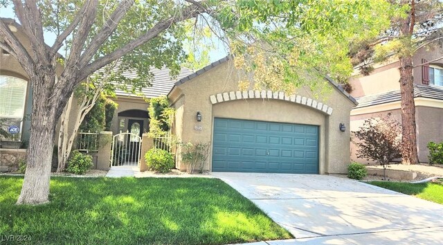 view of front of home with an attached garage, concrete driveway, a tiled roof, a gate, and stucco siding