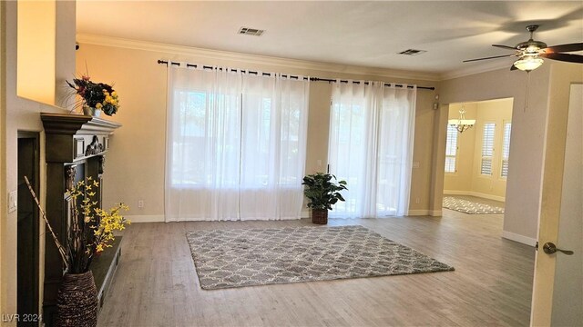 interior space featuring baseboards, wood finished floors, visible vents, and crown molding