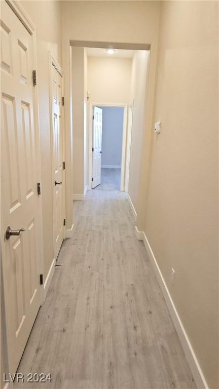 corridor with light wood-type flooring and baseboards