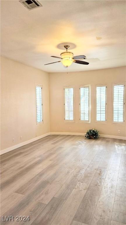 empty room with baseboards, visible vents, and wood finished floors