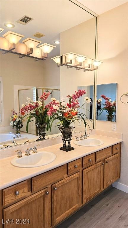 full bathroom featuring double vanity, wood finished floors, a sink, and visible vents