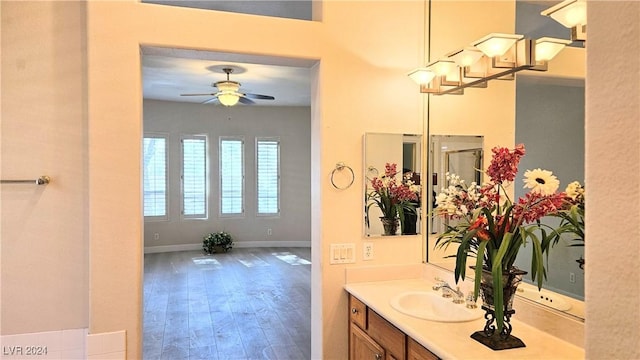 bathroom with a ceiling fan, baseboards, wood finished floors, and vanity