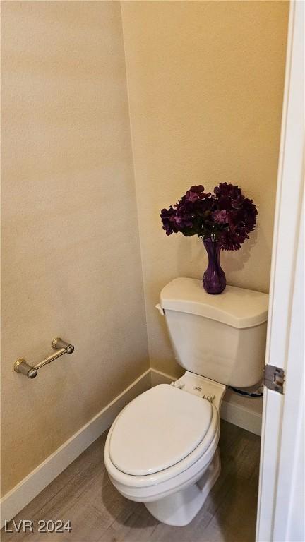 bathroom with toilet, baseboards, and wood finished floors