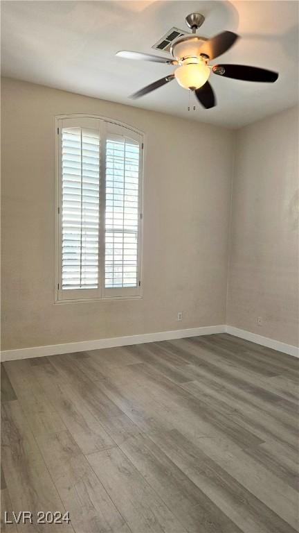 spare room featuring ceiling fan, baseboards, and wood finished floors