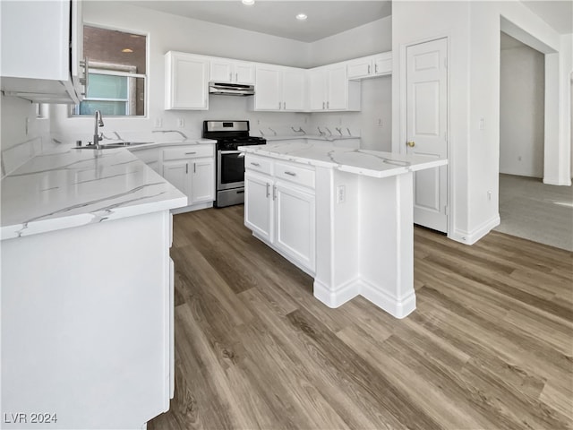 kitchen with white cabinets, sink, gas stove, and a center island