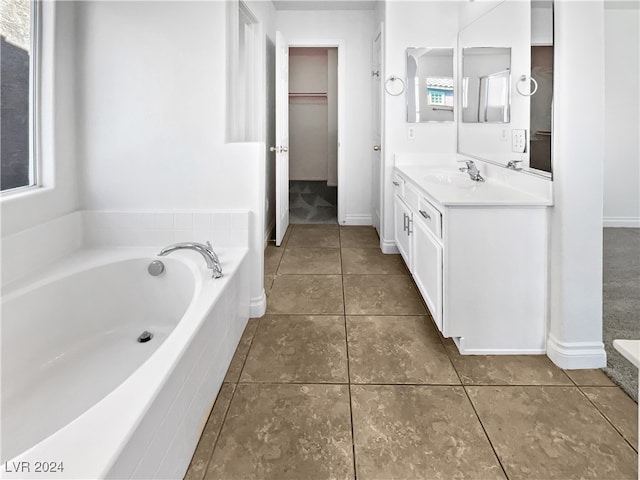 bathroom with tile patterned flooring, tiled tub, and vanity