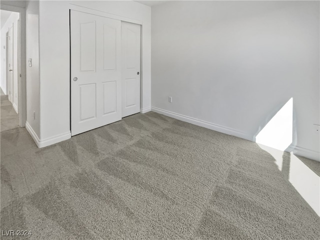 unfurnished bedroom with light carpet and a closet