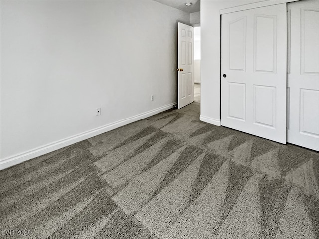 unfurnished bedroom with dark carpet and a closet