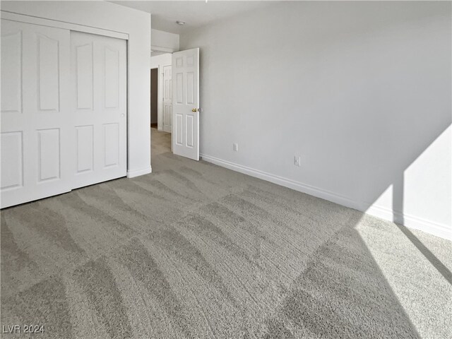 unfurnished bedroom with a closet and light colored carpet