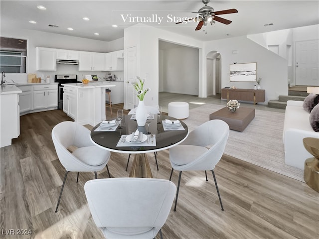 dining space featuring light wood-type flooring, sink, and ceiling fan