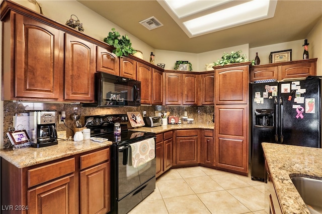 kitchen with black appliances, backsplash, light tile patterned floors, and light stone counters