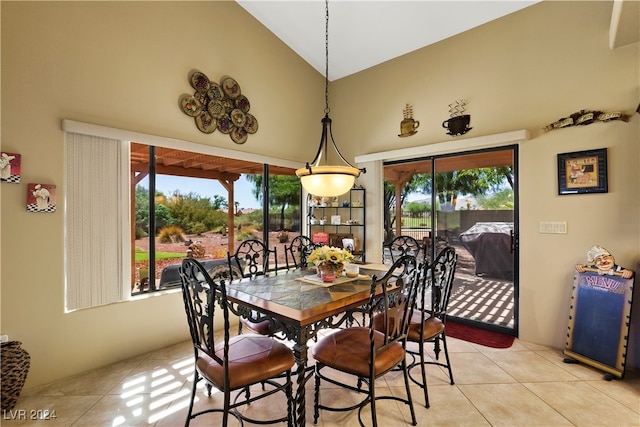 dining room with light tile patterned floors and high vaulted ceiling