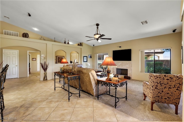 tiled living room with ceiling fan, lofted ceiling, and a tile fireplace