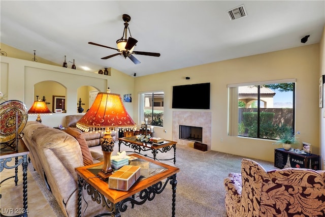 living room featuring lofted ceiling, ceiling fan, a tile fireplace, and light colored carpet