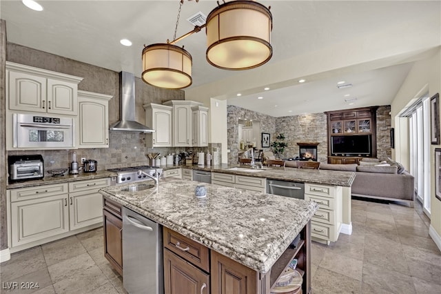 kitchen featuring white cabinets, sink, kitchen peninsula, a kitchen island with sink, and wall chimney range hood