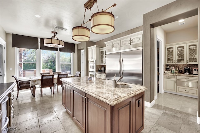 kitchen featuring decorative backsplash, pendant lighting, stainless steel appliances, a center island with sink, and sink