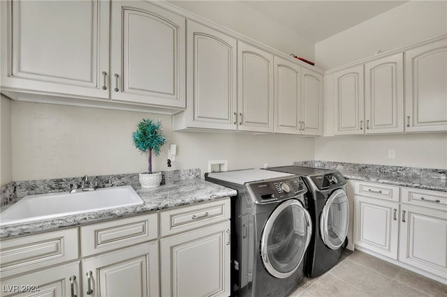 clothes washing area with cabinets, light tile patterned floors, separate washer and dryer, and sink