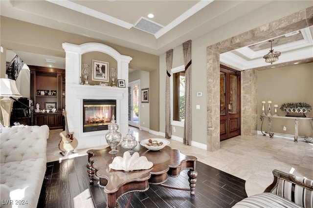 living room featuring a multi sided fireplace, a tray ceiling, crown molding, and light hardwood / wood-style flooring