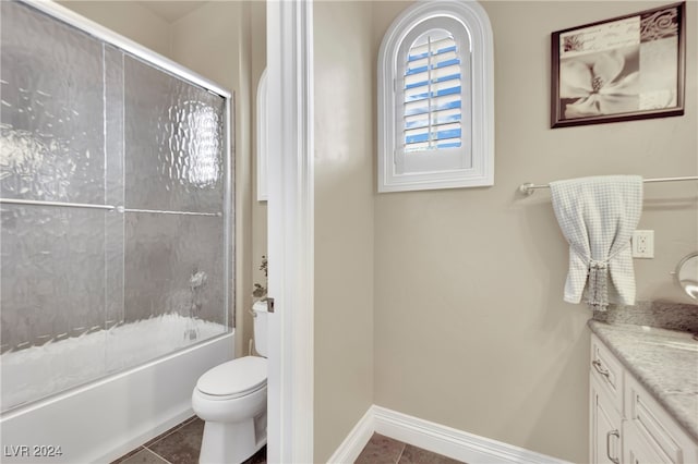 full bathroom with combined bath / shower with glass door, vanity, toilet, and tile patterned floors