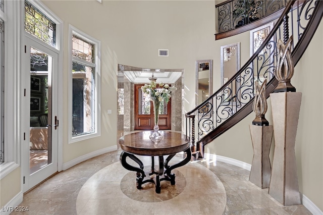 entrance foyer featuring a healthy amount of sunlight, crown molding, and a towering ceiling