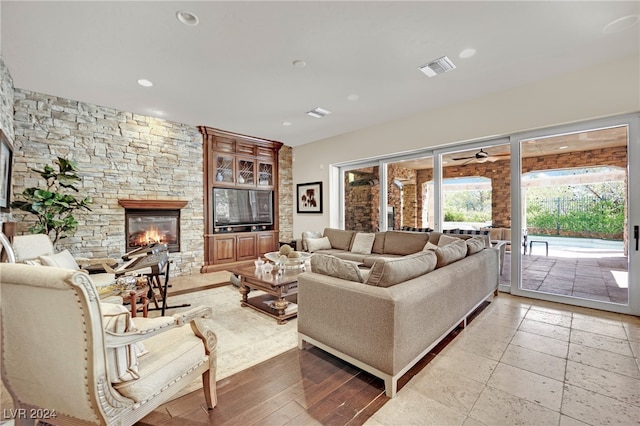 living room featuring a stone fireplace, ceiling fan, and light hardwood / wood-style flooring