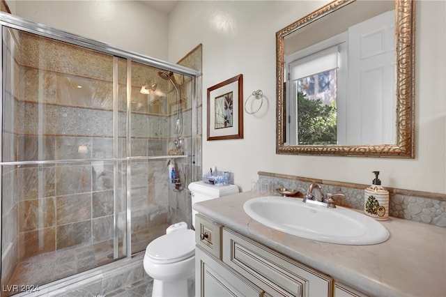 bathroom with vanity, toilet, and a shower with shower door