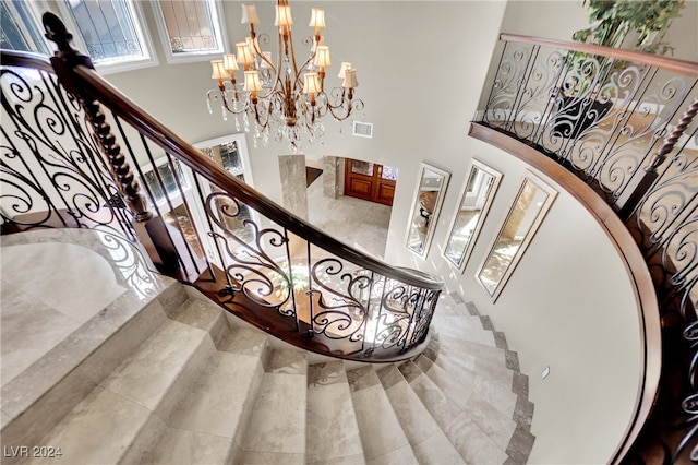 staircase with an inviting chandelier and a towering ceiling