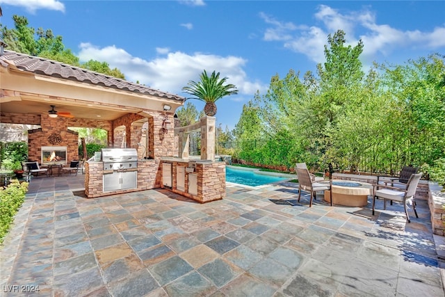 view of patio / terrace with exterior kitchen, area for grilling, ceiling fan, and an outdoor fire pit