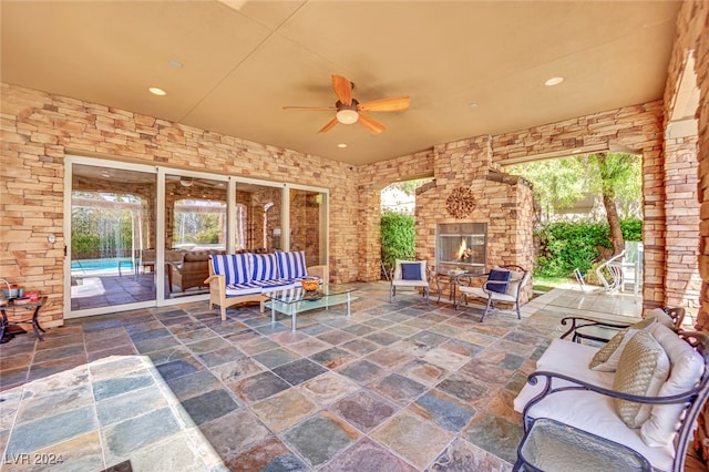 view of patio / terrace featuring an outdoor living space with a fireplace and ceiling fan