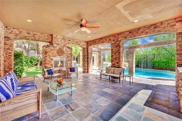 view of patio / terrace featuring ceiling fan and an outdoor living space with a fireplace