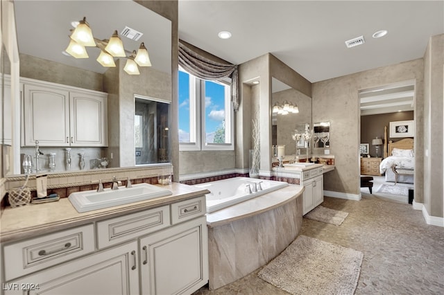 bathroom featuring an inviting chandelier, a relaxing tiled tub, and vanity