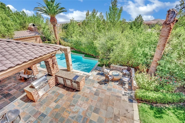 view of pool with a patio, a fire pit, and exterior kitchen