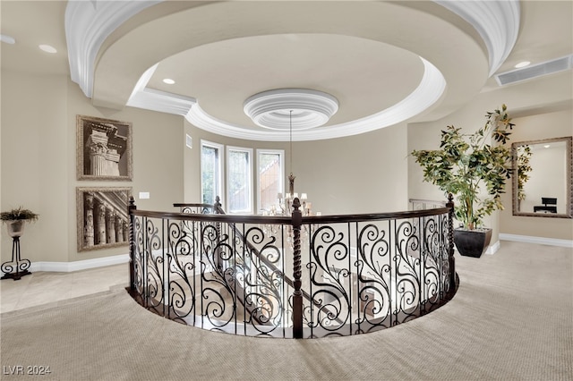 hallway featuring ornamental molding, a tray ceiling, light carpet, and a chandelier