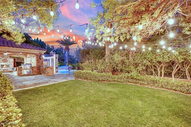 yard at dusk with exterior kitchen and a patio