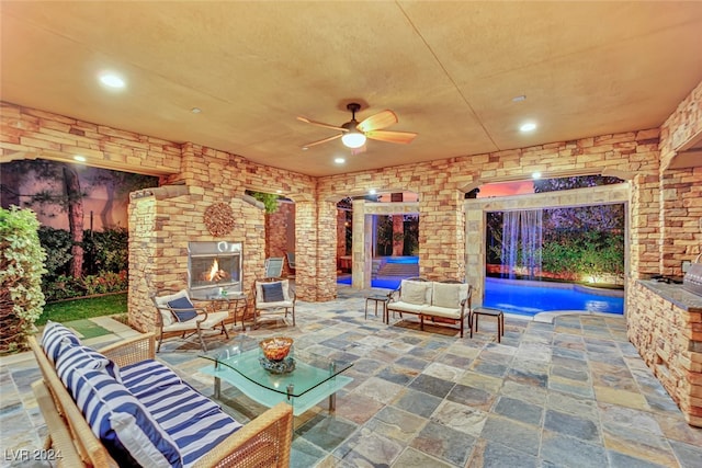 view of patio / terrace featuring ceiling fan and an outdoor living space with a fireplace