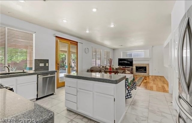 kitchen featuring stainless steel appliances, white cabinetry, a healthy amount of sunlight, and sink