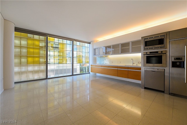 kitchen with built in appliances, floor to ceiling windows, and sink