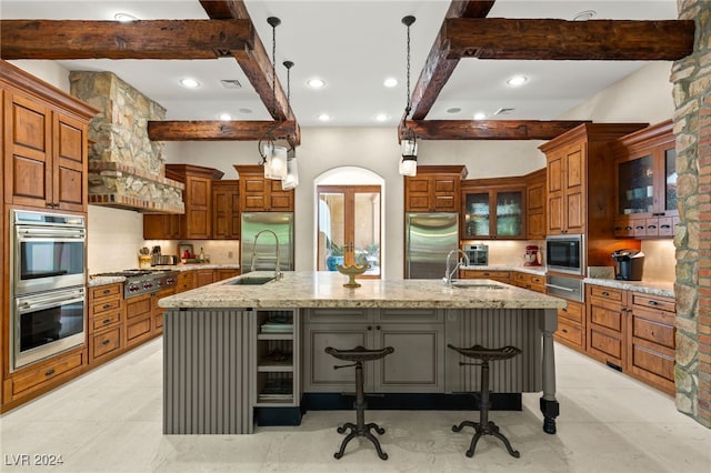 kitchen featuring hanging light fixtures, light stone counters, stainless steel appliances, a large island, and a kitchen bar