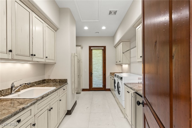 kitchen with light tile patterned floors, dark stone countertops, sink, and independent washer and dryer