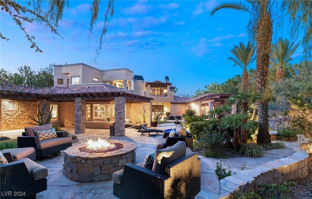 patio terrace at dusk featuring an outdoor living space with a fire pit