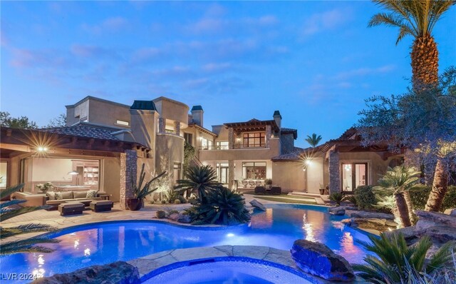 pool at dusk with an outdoor living space, a patio area, and an in ground hot tub