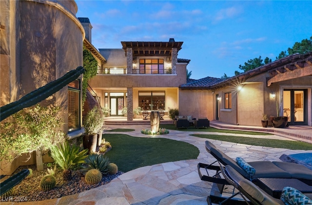 back house at dusk with a patio area