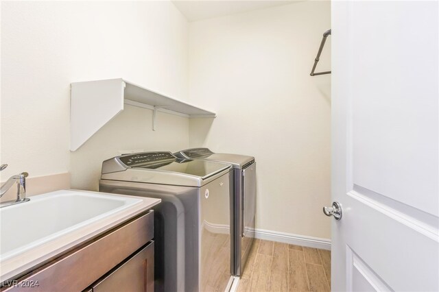 laundry area with cabinets, light hardwood / wood-style flooring, sink, and washer and clothes dryer