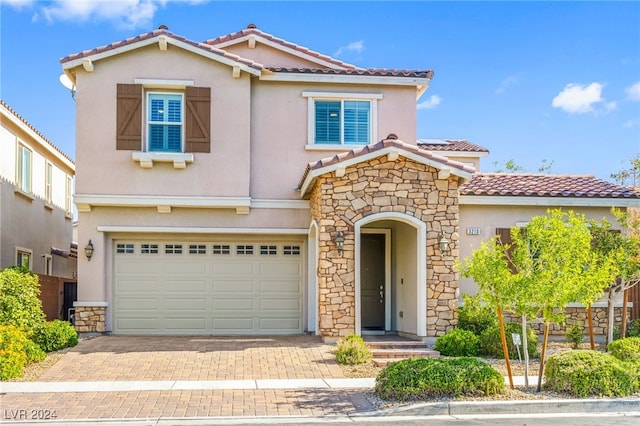 view of front facade featuring stone siding, a tiled roof, an attached garage, stucco siding, and decorative driveway