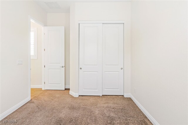 unfurnished bedroom featuring a closet and light carpet