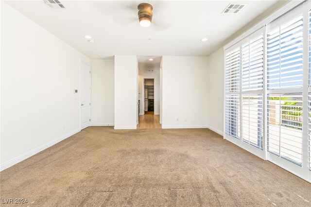 carpeted empty room with ceiling fan and a wealth of natural light