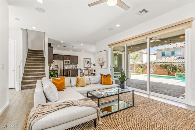 living room with ceiling fan, sink, and light wood-type flooring