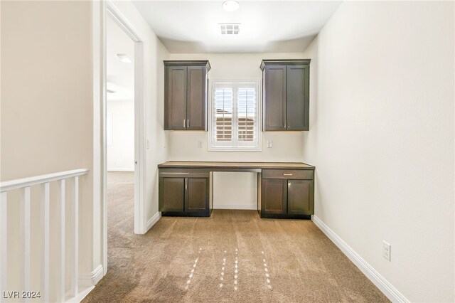 interior space featuring light carpet, dark brown cabinetry, and built in desk