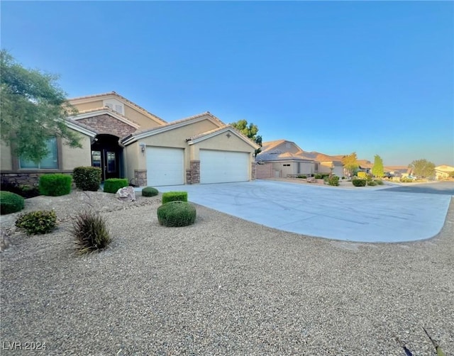 ranch-style home with a tiled roof, an attached garage, stone siding, stucco siding, and driveway
